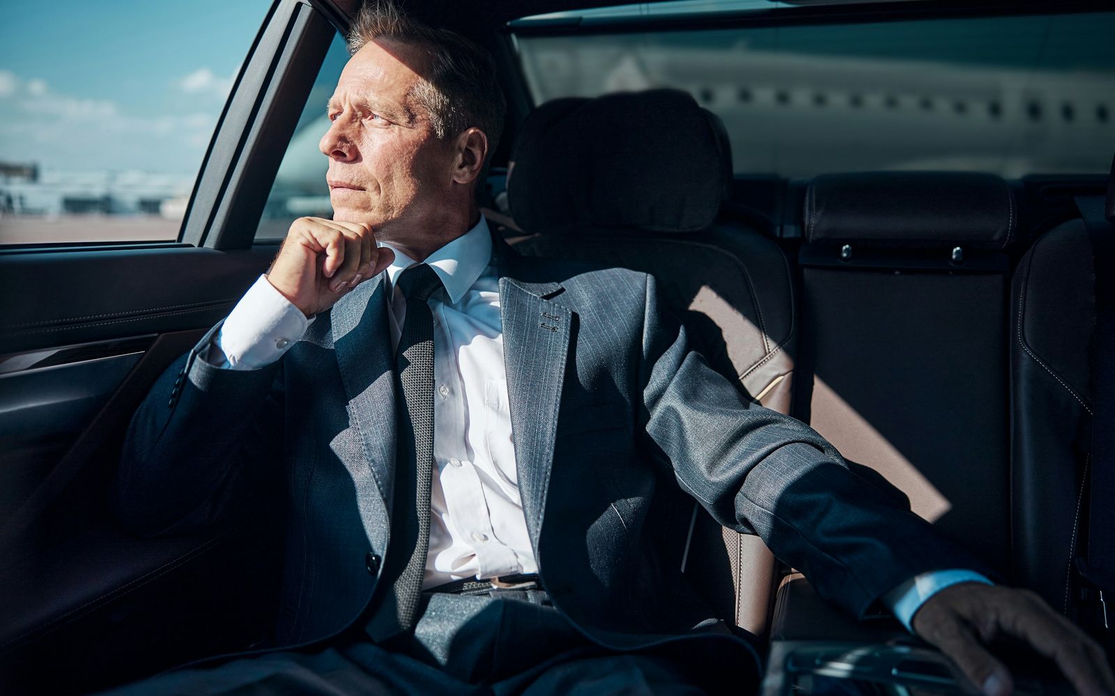 Businessman looking out of the window from the back of a Mercedes