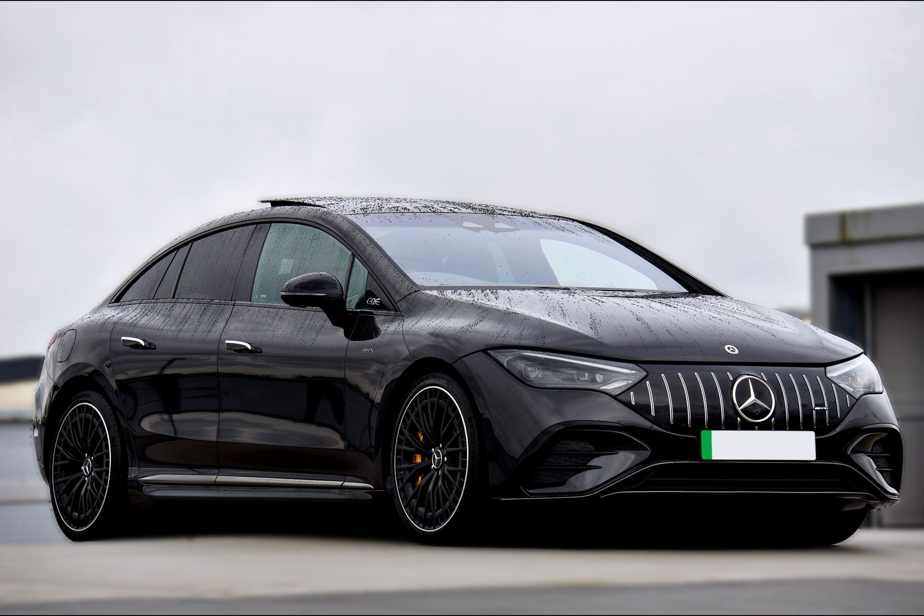 Black all-electric Mercedes EQE saloon parked outdoors on an overcast day