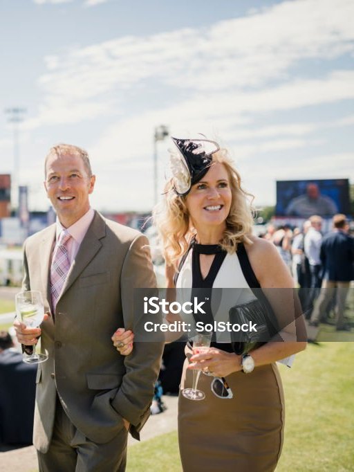 Smartly dressed couple with drinks at the racecourse on race day