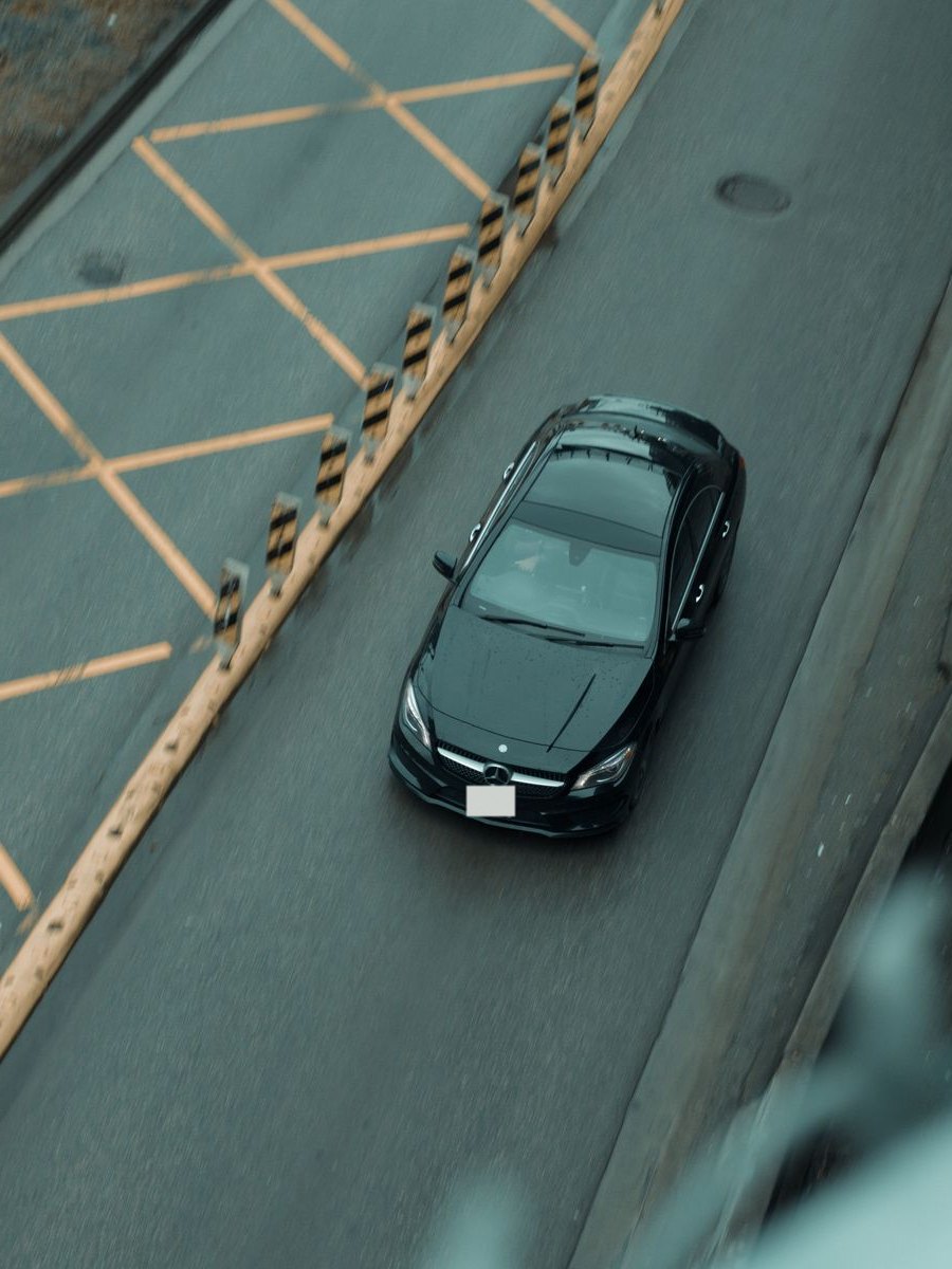 Black Mercedes seen from above, driving along a city road