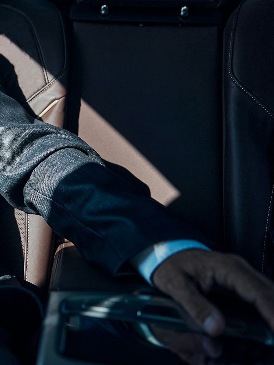 Businessman's hand resting on a tablet in the back of a car